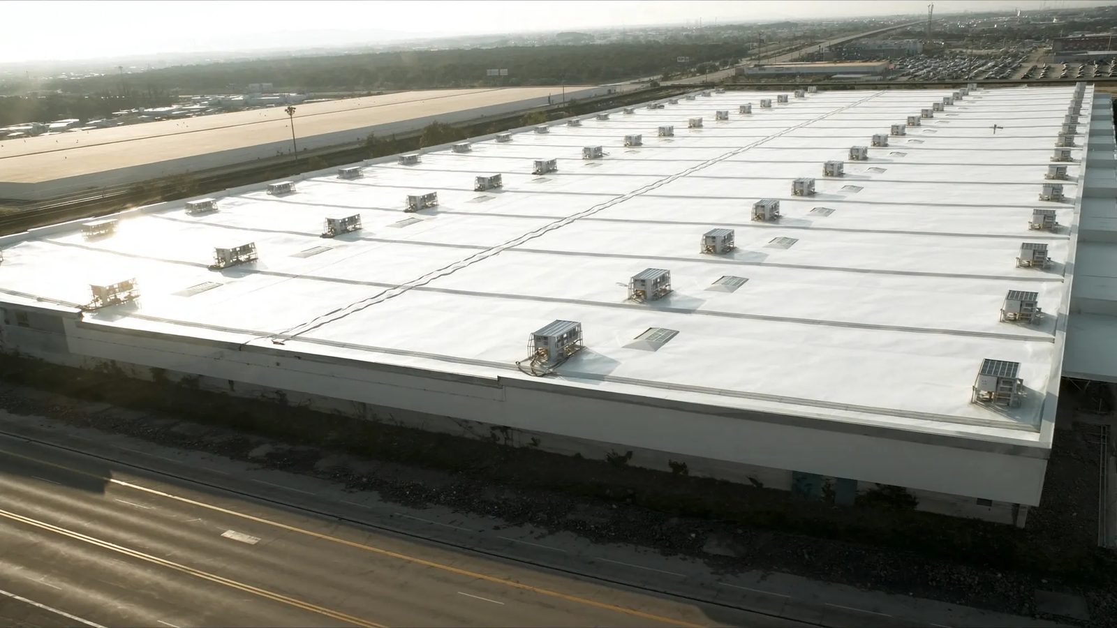 Aerial view of a large commercial building with a white TPO roof