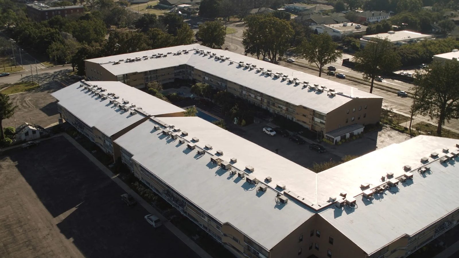 Aerial view of a garden-style apartment complex with white low-slope roofs